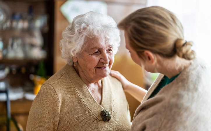 Adult daughter speaking gently with her elderly mother at home, offering reassurance and support